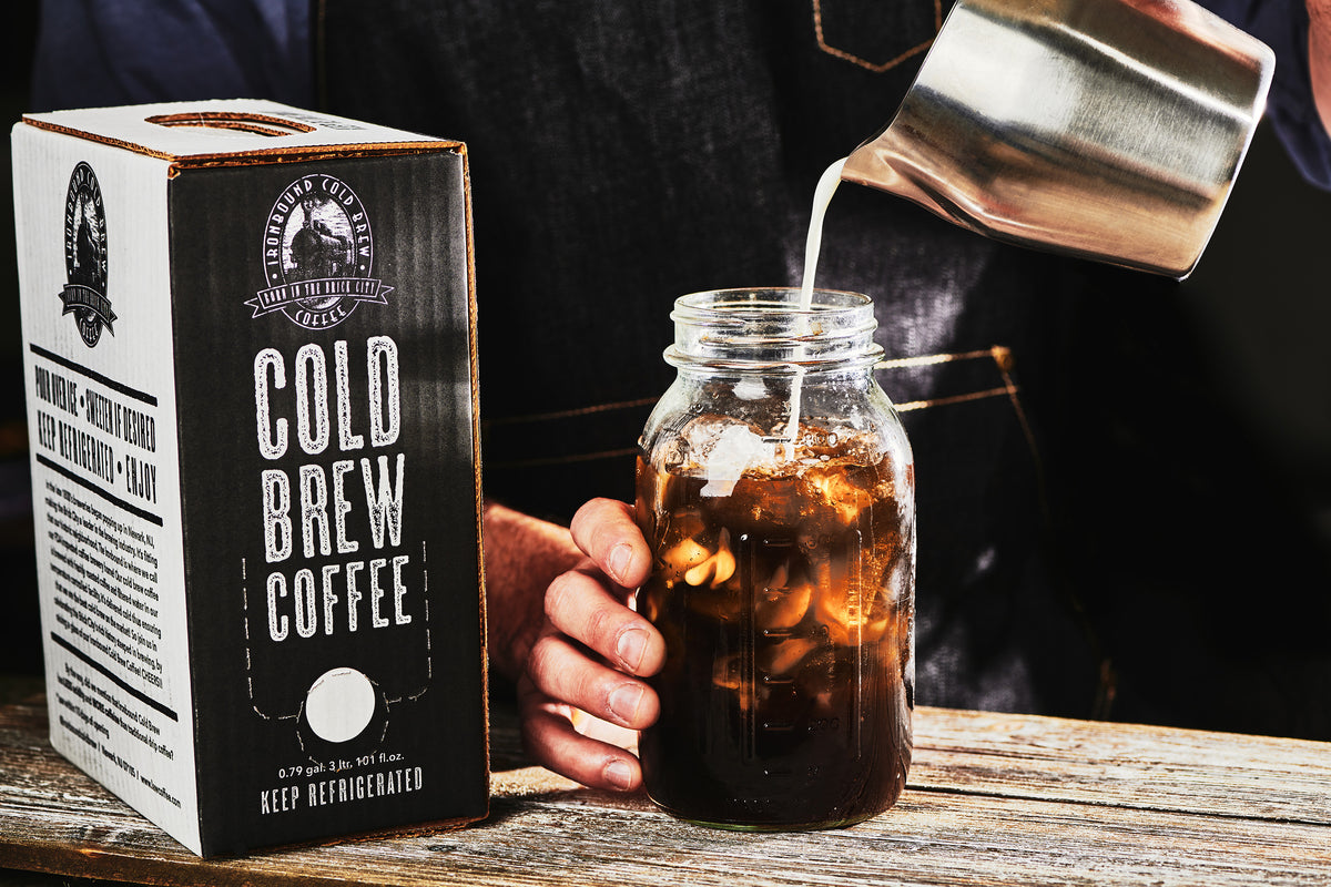 Barista pouring milk into a mason jar of Ironbound cold brew coffee