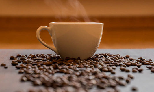 Ceramic cup of coffee siting amongst coffee beans