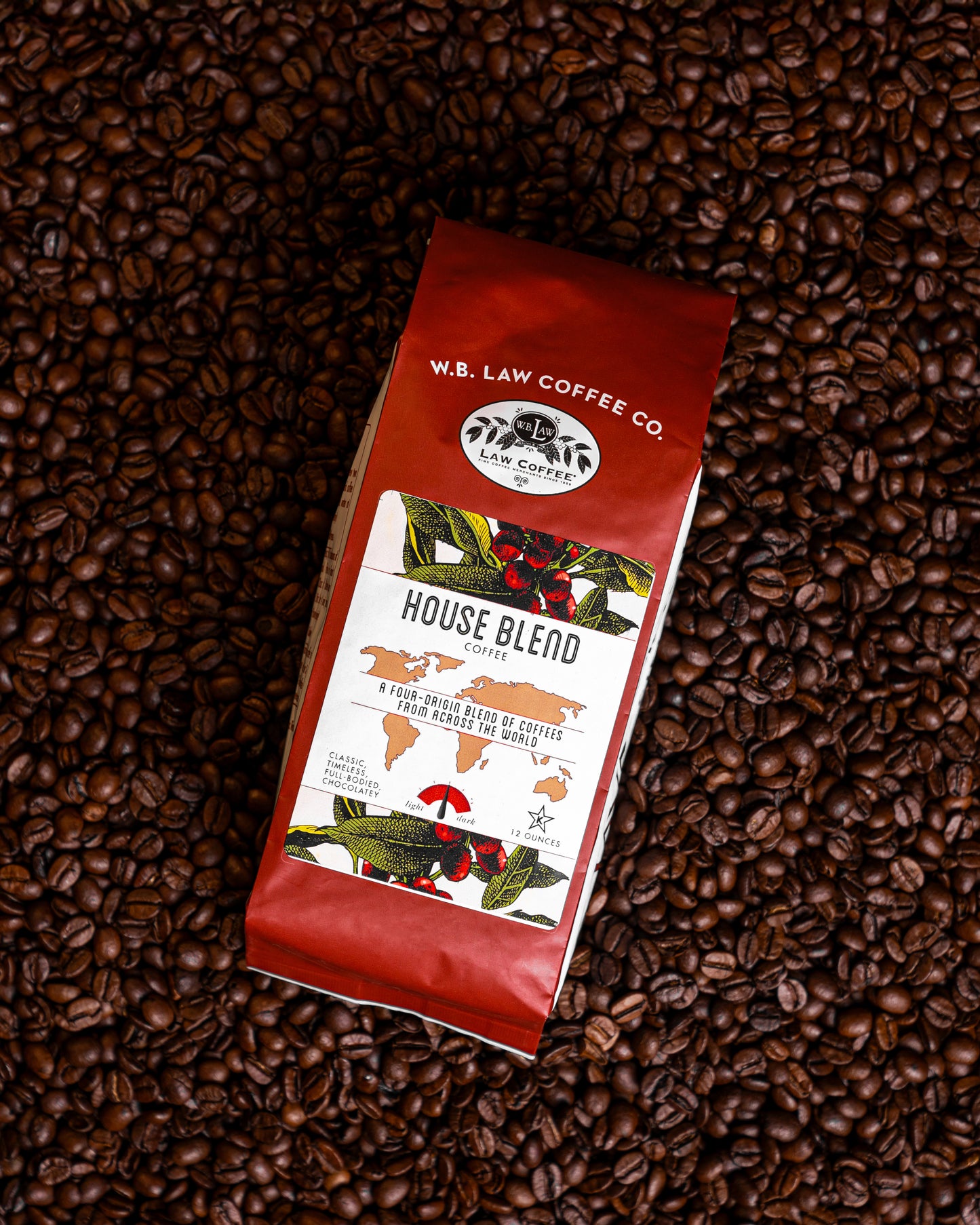 A 12oz bag of House Blend coffee beans from W.B. Law Coffee Co. placed on a background of whole coffee beans.