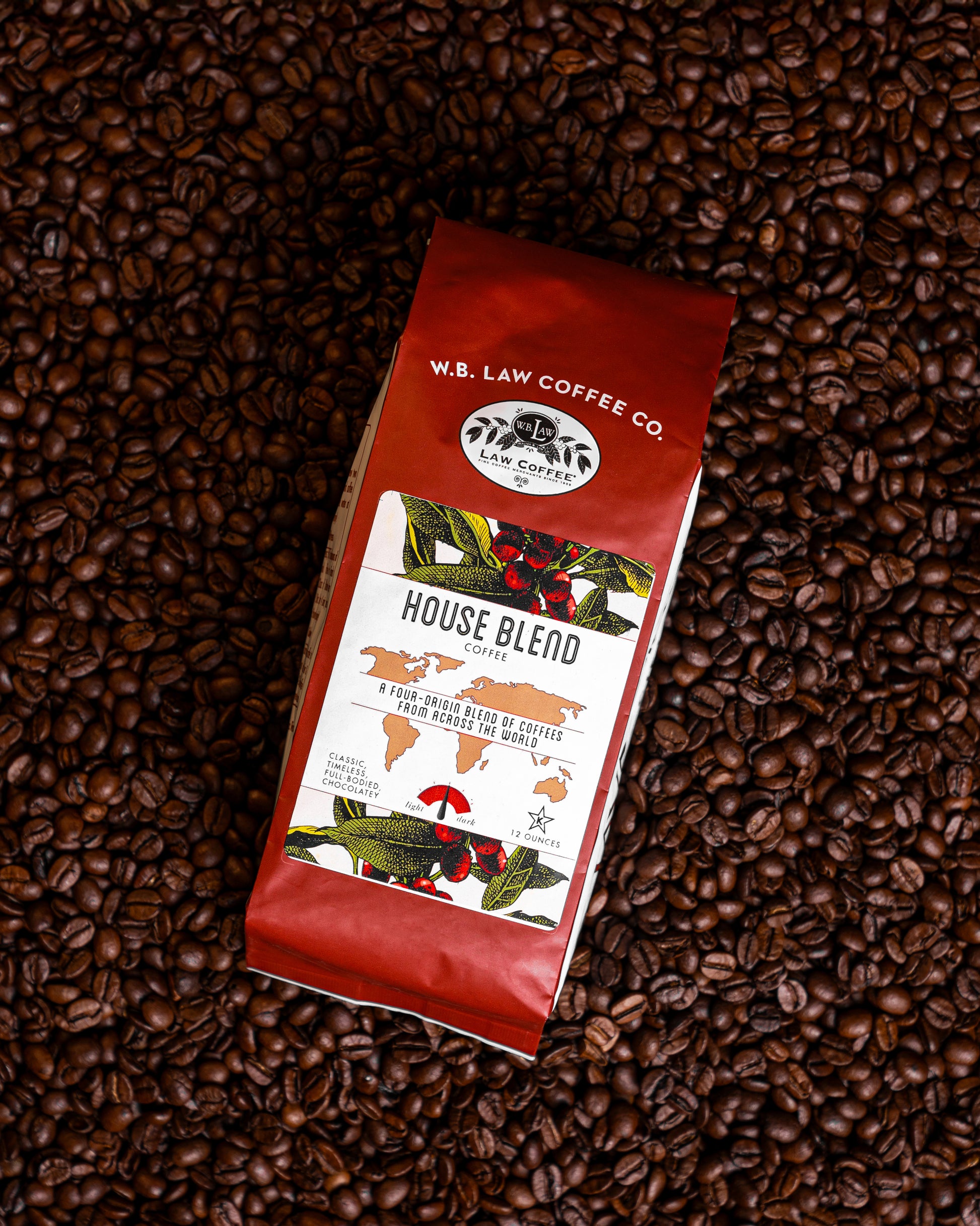 A 12oz bag of House Blend coffee beans from W.B. Law Coffee Co. placed on a background of whole coffee beans.