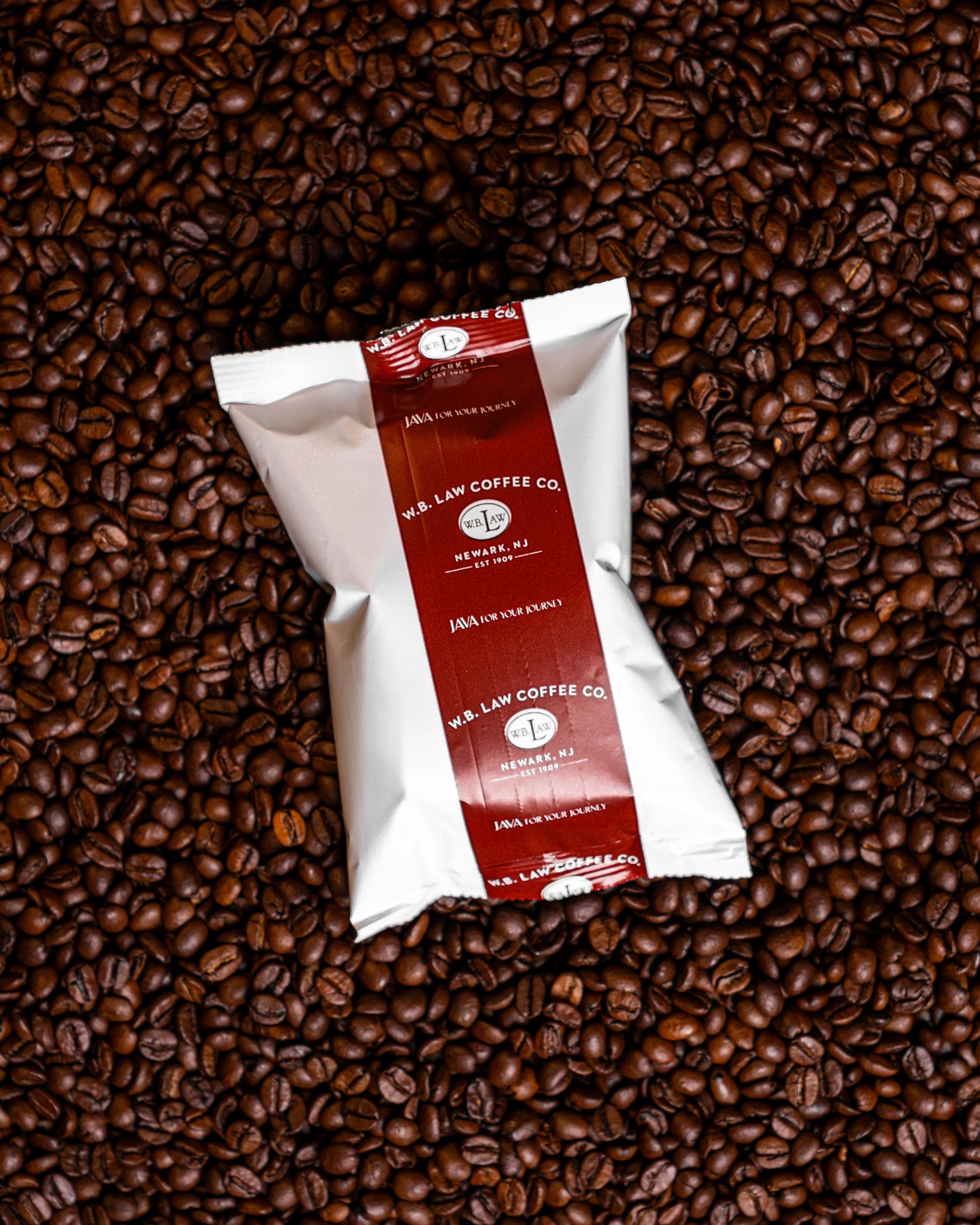 A 2.5oz bag of ground Laws Colombian coffee, placed on a background of whole coffee beans.