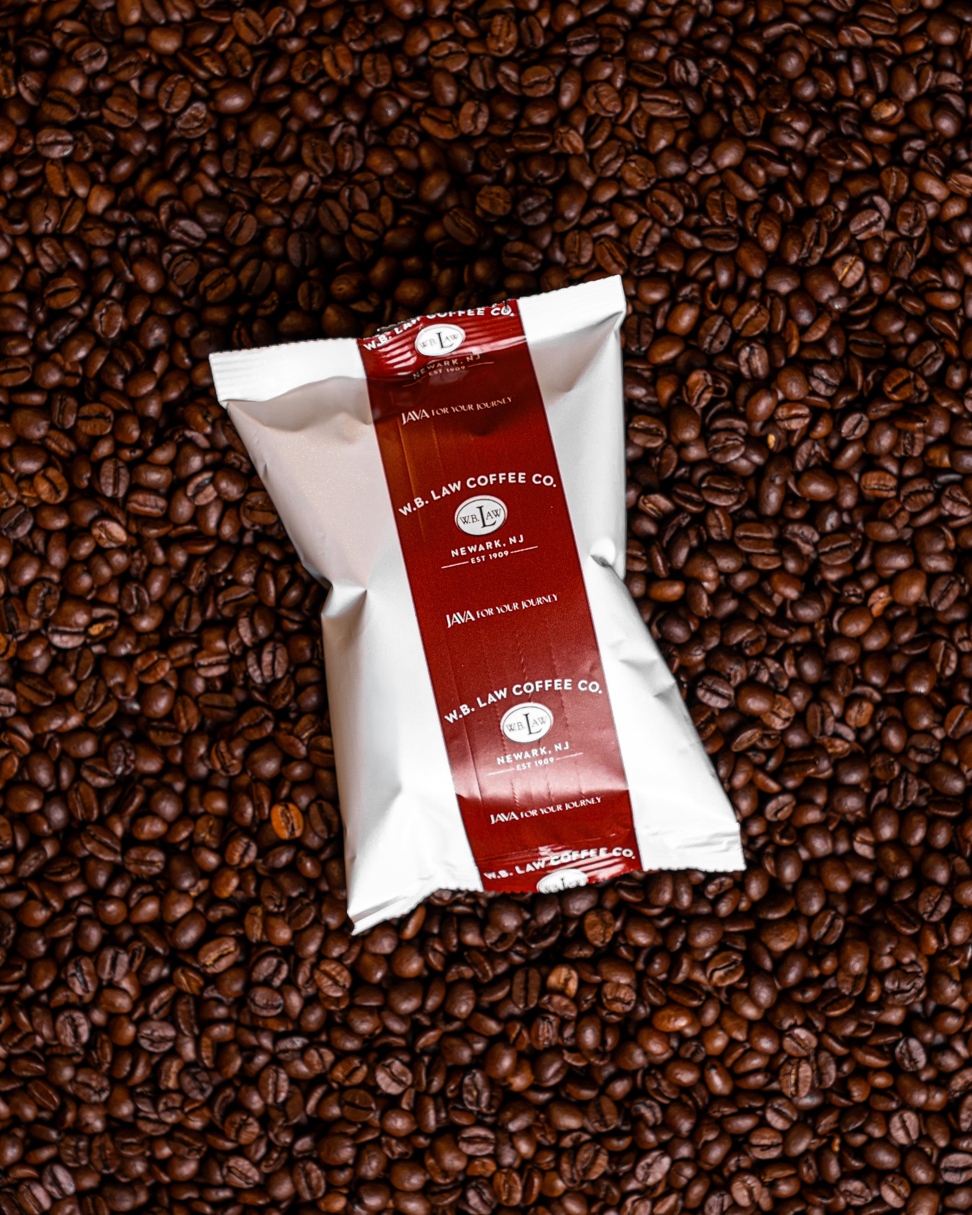A 2.5oz bag of ground Laws Colombian coffee, placed on a background of whole coffee beans.