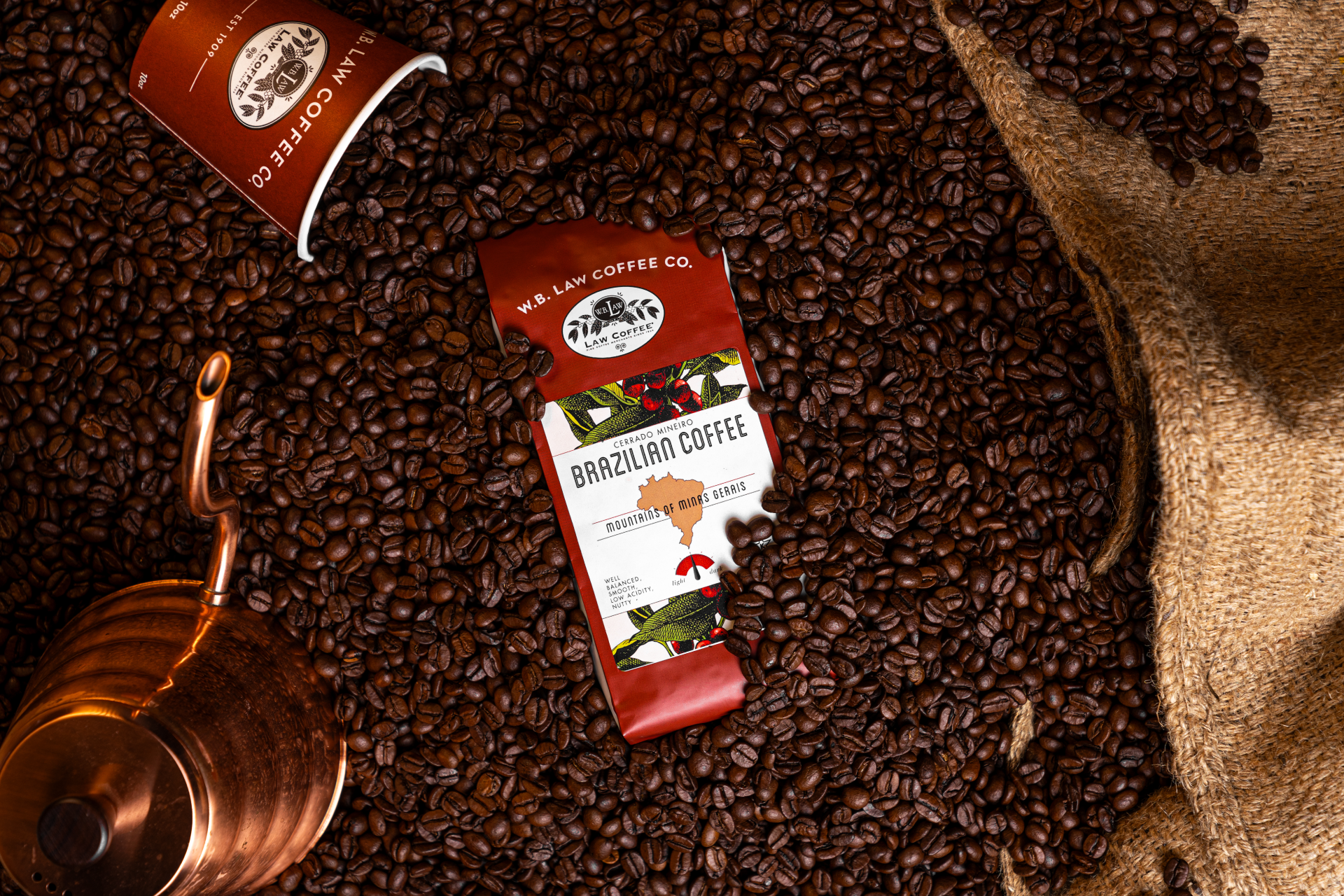 A 12oz retail bag of Brazil Cerrado Coffee sitting in a pile of coffee beans.