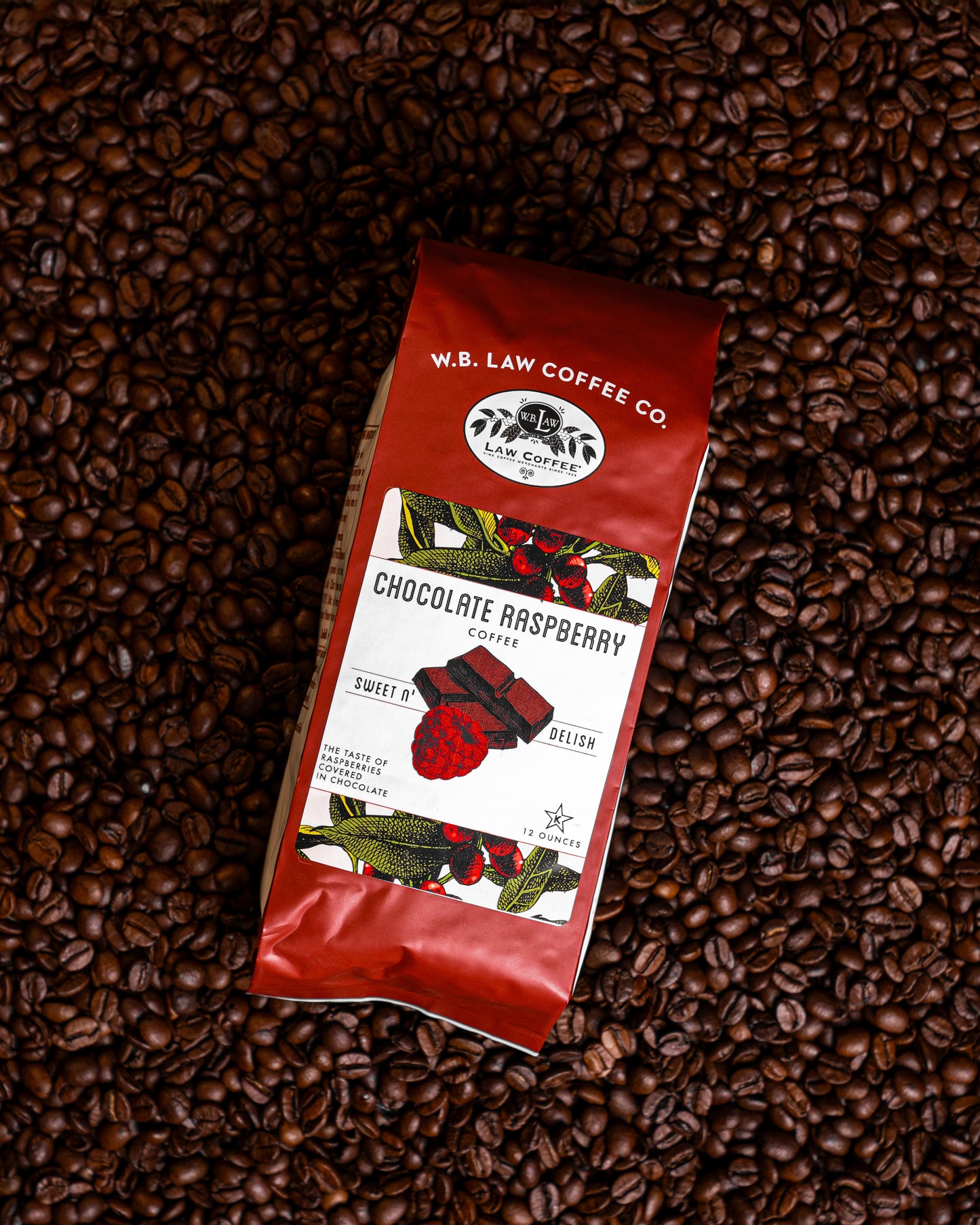A 12oz bag of our chocolate raspberry coffee sitting on a pile of coffee beans.