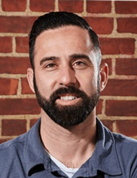 A photo of David Mendez standing in front of a brick wall. 