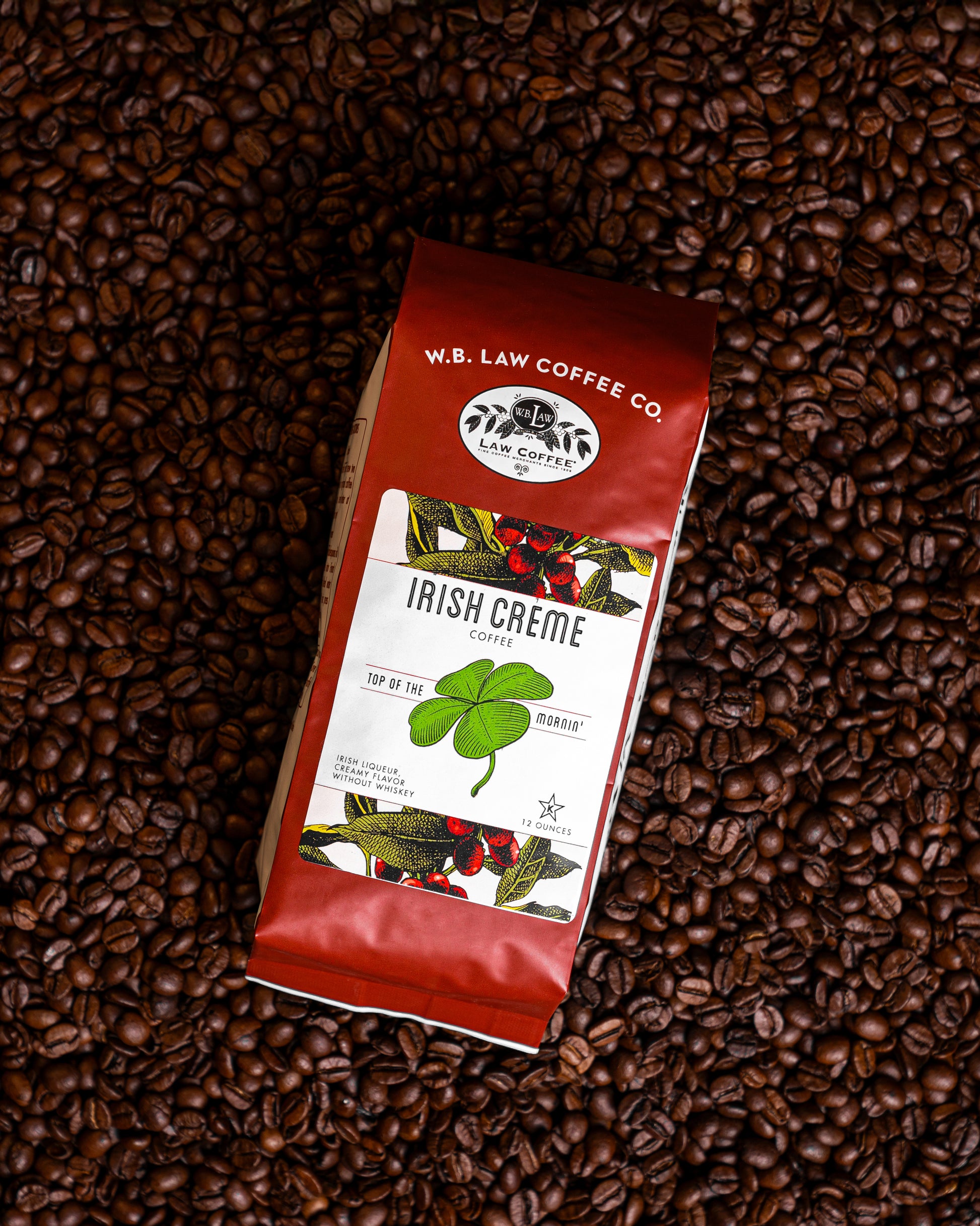 A 12oz bag of W. B. Law Coffee Co. Irish Creme coffee on top of a background of coffee beans.