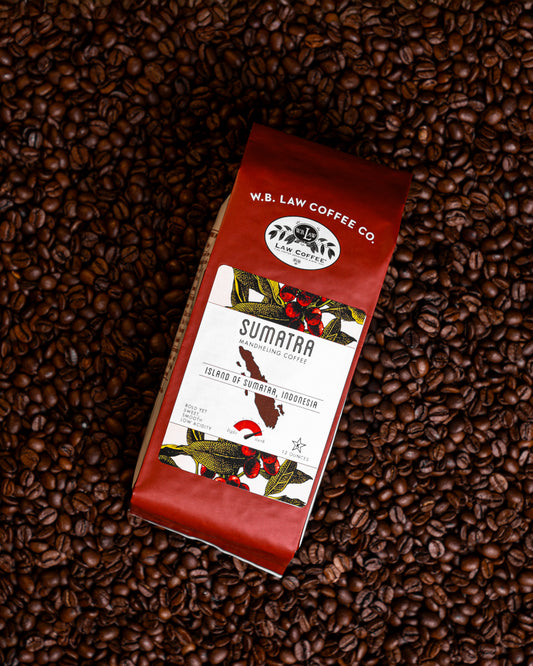 A bag of a bold roasted WB Law Coffee Sumatran Mandheling coffee sitting on a pile of coffee beans.